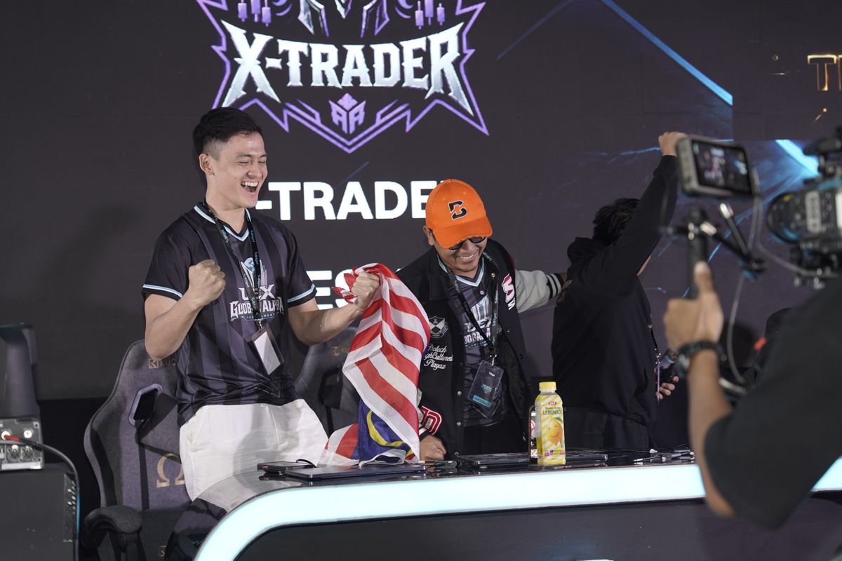 Kyle meraikan kemenangan pasukan X-TRADER di atas pentas, dengan bendera Malaysia